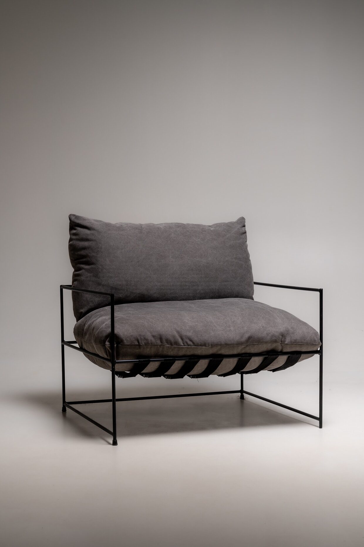 Moderner Lounge-Sessel mit grauem Stoffbezug und schwarzem Metallrahmen in minimalistischem Studio-Setup