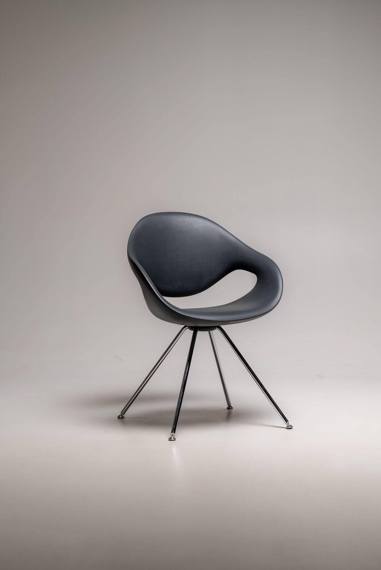 Dunkelgrauer Designstuhl mit ergonomischer Sitzschale und Metallbeinen freigestellt im Studio