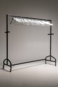 Schwarze mobile Kleiderstange mit weißen Kleiderbügeln freigestellt im Studio