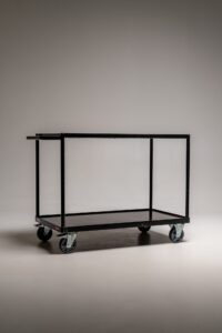Schwarzer Metall-Rollwagen mit zwei Ablageflächen auf Rollen freigestellt im Fotostudio für Requisiten und Equipment