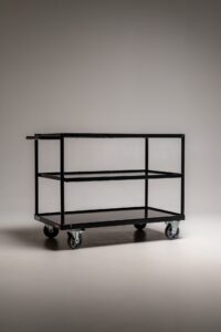 Schwarzer Metall-Rollwagen mit drei Ablageflächen auf Rollen freigestellt im Fotostudio für Requisiten und Equipment