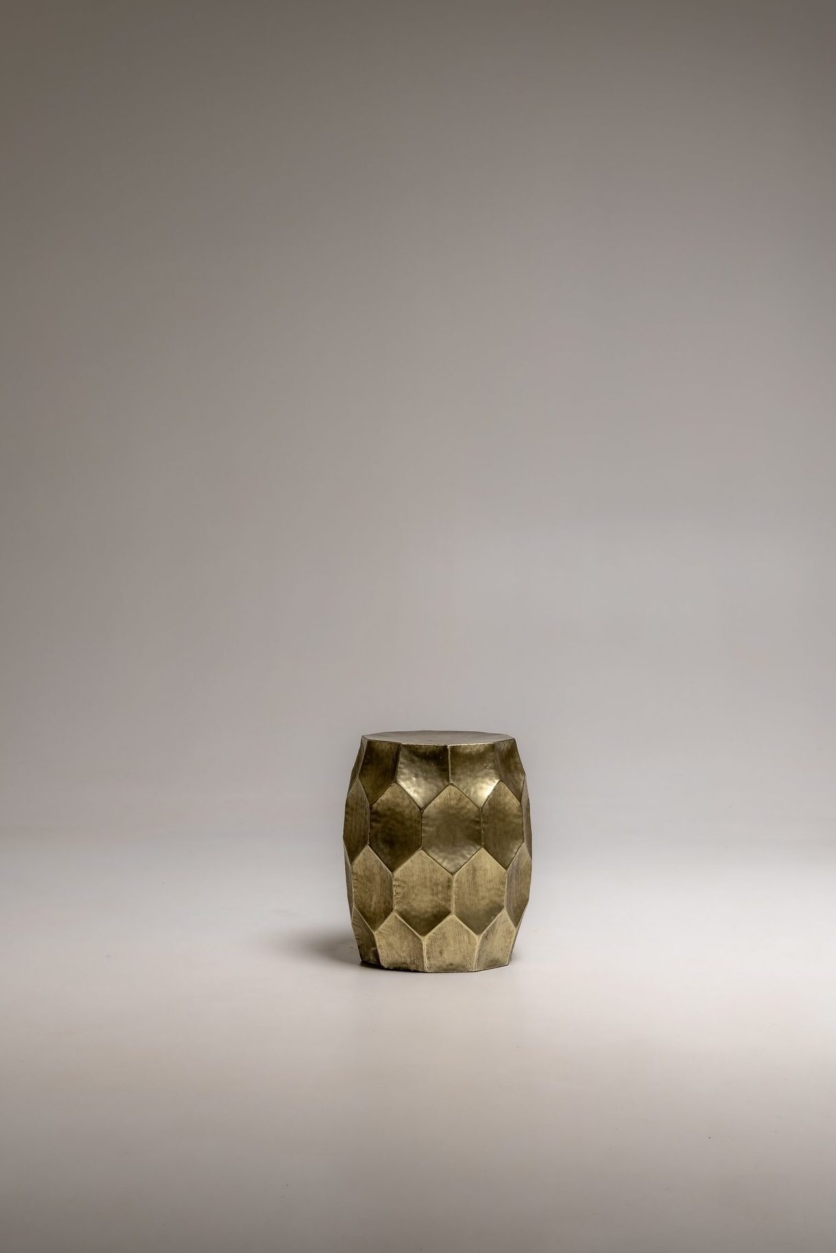 Kleiner Beistelltisch aus Metall mit geometrischer Struktur in Goldoptik freigestellt im Studio