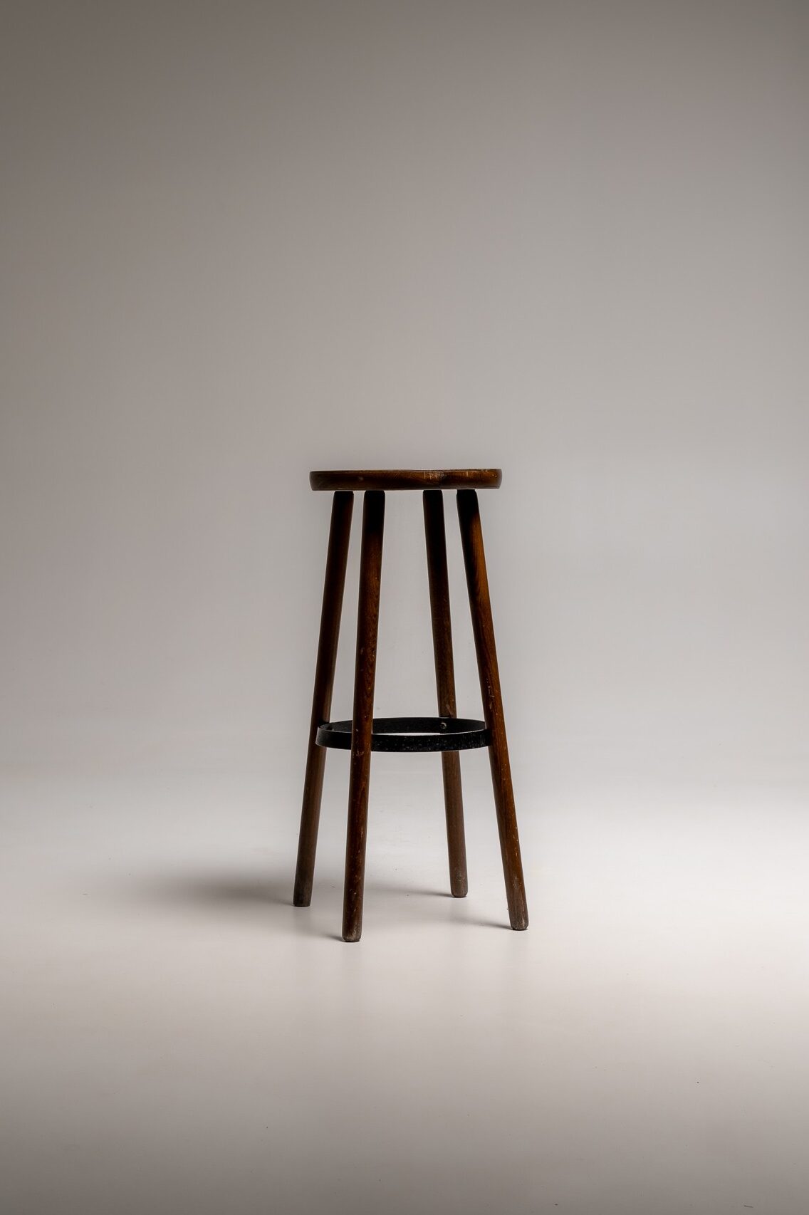 Hoher Barhocker mit rundem Holzsitz und schwarzem Metallgestell freigestellt vor hellem Hintergrund